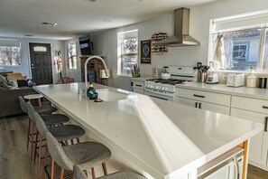 A modern kitchen with a large island, bar stools, a stove, and a built-in oven. - Flagstaff Home Near NAU with Easy Access to Snowbowl, Grand Canyon, and Downtown (Flagstaff)