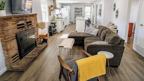 Ett modernt vardagsrum med en öppen spis, en soffa, ett soffbord och en tv som är monterad på väggen.