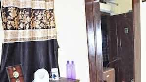 A small room with a wooden desk, a mirror, a cabinet, and a table with a kettle and teapot. - Sarla Resort (Sawai Madhopur)