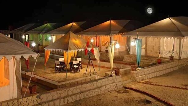 A series of tents with a dining area in the center, surrounded by stone steps and a small garden. - Sarla Resort (Sawai Madhopur)