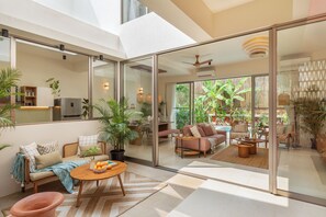 Un vaste espace de vie comprenant un canapé, une table basse et des plantes en pot.