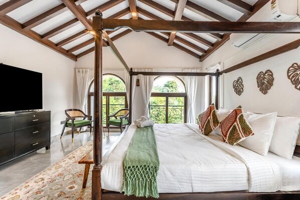 A bedroom with a wooden ceiling, a bed with white bedding, a green throw, and heart-shaped wall decorations.