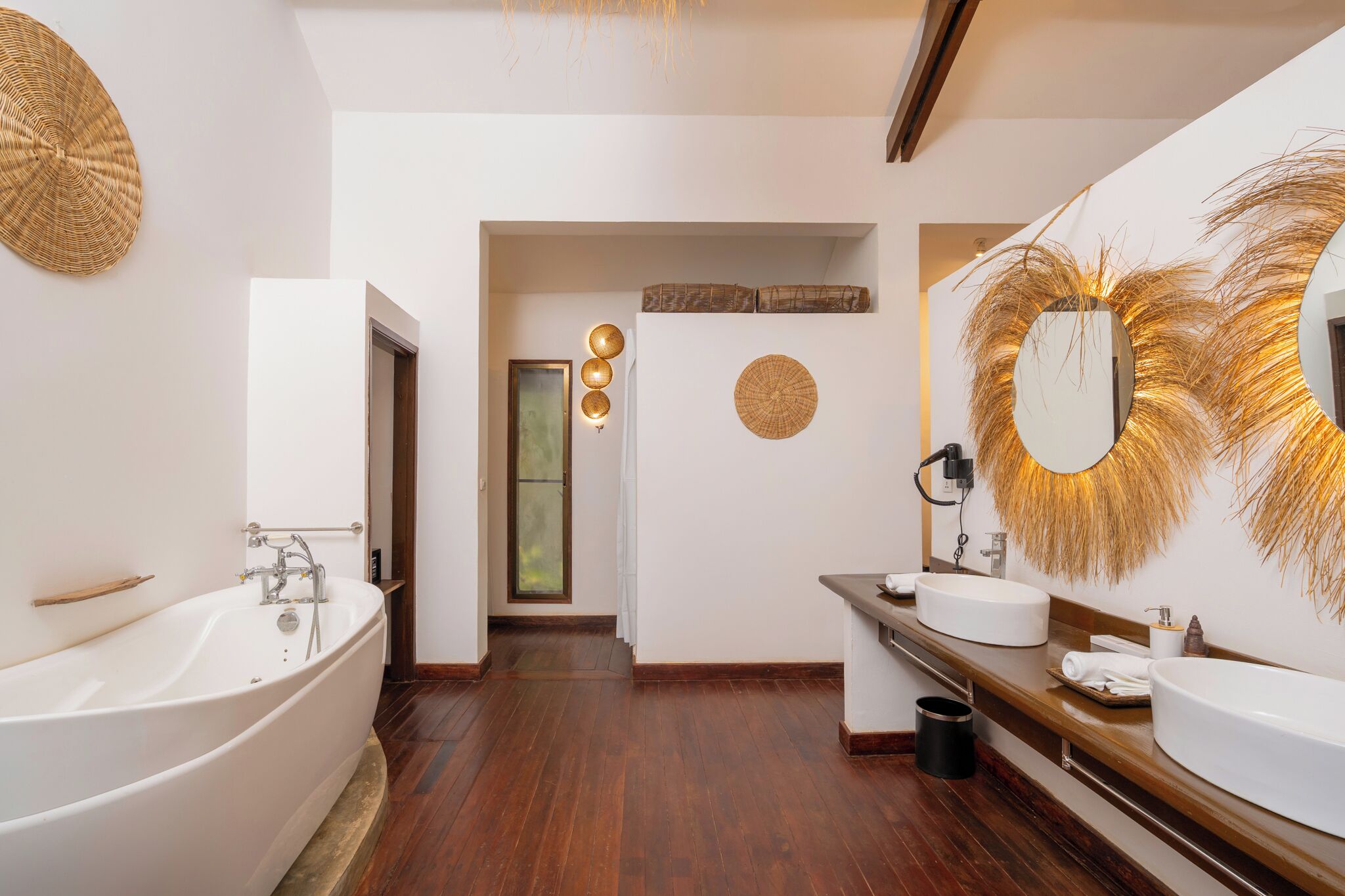 A modern bathroom with a freestanding bathtub, two sinks, and decorative wall art.