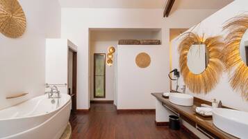 A modern bathroom with a freestanding bathtub, two sinks, and decorative wall art.