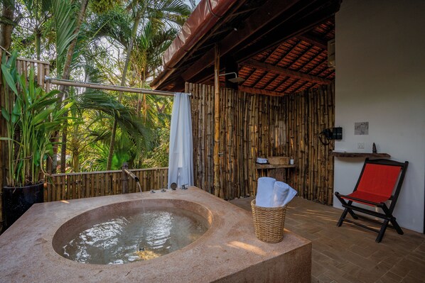 A hot tub with a bamboo backdrop, a wicker basket with towels, and a red chair. - Kampung Kamboja (Siem Reap)