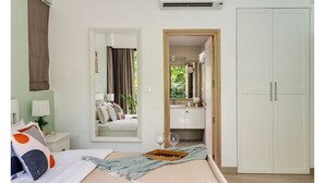 Ein Schlafzimmer mit Bett, Nachttisch, Spiegel, Kleiderschrank und Klimaanlage.