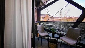 En balkong med två stolar, ett litet bord och en krukväxt.