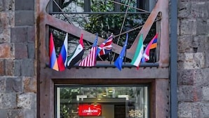 En byggnadsentré med en glasdörr, en skylt med texten ”LONDON” och flera flaggor som hänger ovanför.