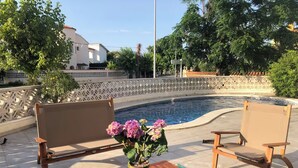 Un espace aménagé au bord de la piscine, avec un banc en bois, une petite table et un pot de fleurs.