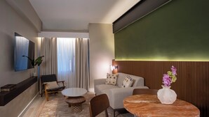 Una sala de estar moderna con un sofá, dos sillones, una mesa de centro y un televisor montado en la pared.