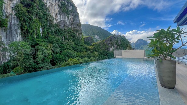 Una piscina con agua azul cristalina, rodeada de vegetación exuberante y acantilados escarpados.