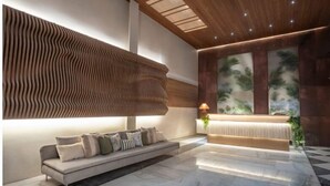 Un vestíbulo moderno con un sofá, una mesa de recepción y un muro con diseño.