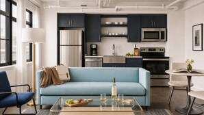 A modern kitchen with dark cabinets, stainless steel appliances, and a light blue sofa in a living area.