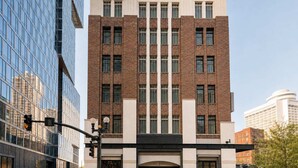 A multi-story building with a brick facade, large windows, and a modern entrance with a black awning.