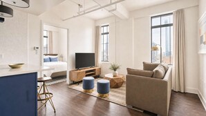 A modern living room with a sofa, TV, and a dining area with a table and chairs.