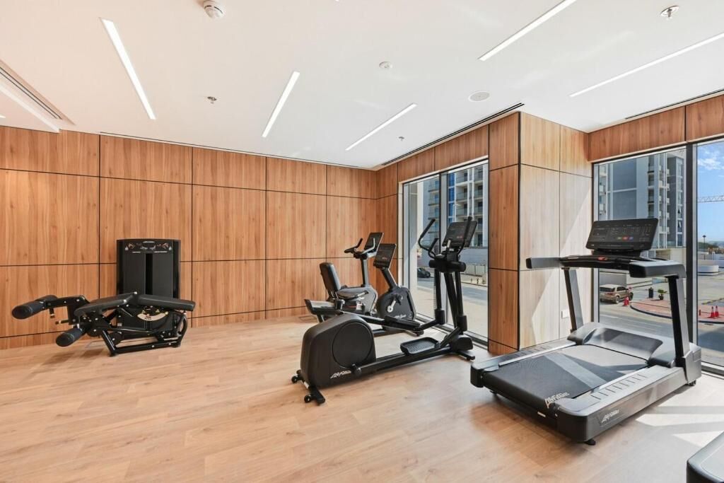A modern gym with cardio machines, a rowing machine, and a treadmill.