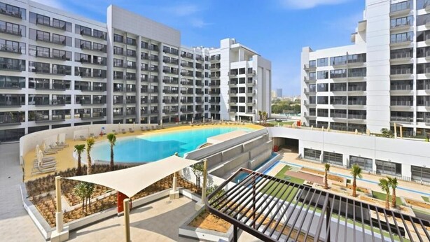 A modern hotel with multiple floors, a swimming pool, and outdoor seating areas. - Bloomfields Sleek 1BR in Azizi Mirage 1 (Dubai)