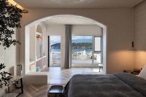 Et soveværelse med en stor seng, havudsigt og en balkon med udendørs møbler.