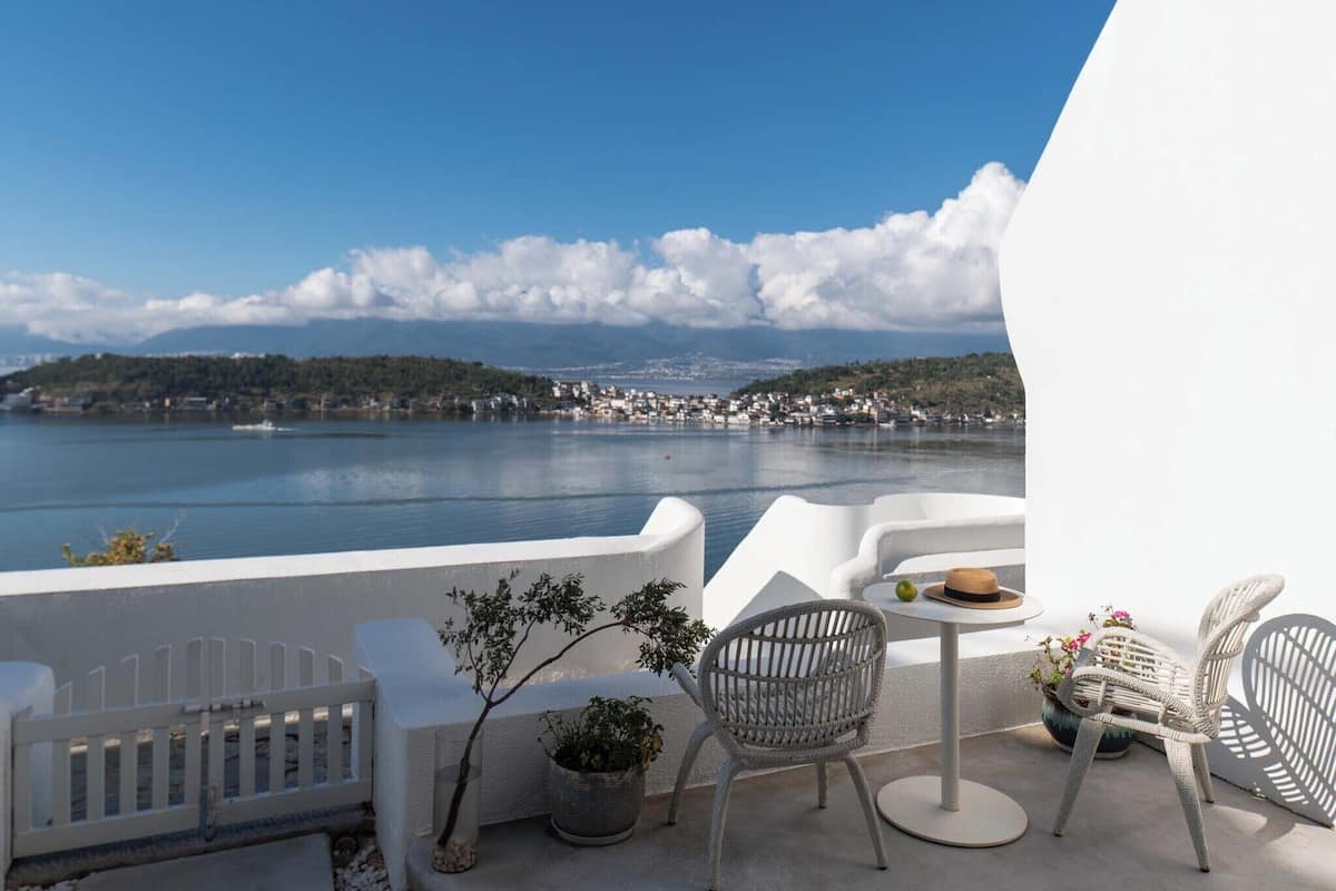 Un balcon avec des meubles blancs, une petite table et une plante en pot.