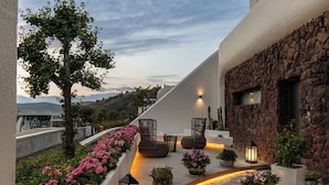 Un patio moderno al aire libre con mobiliario, un muro de piedra y vistas del paisaje.