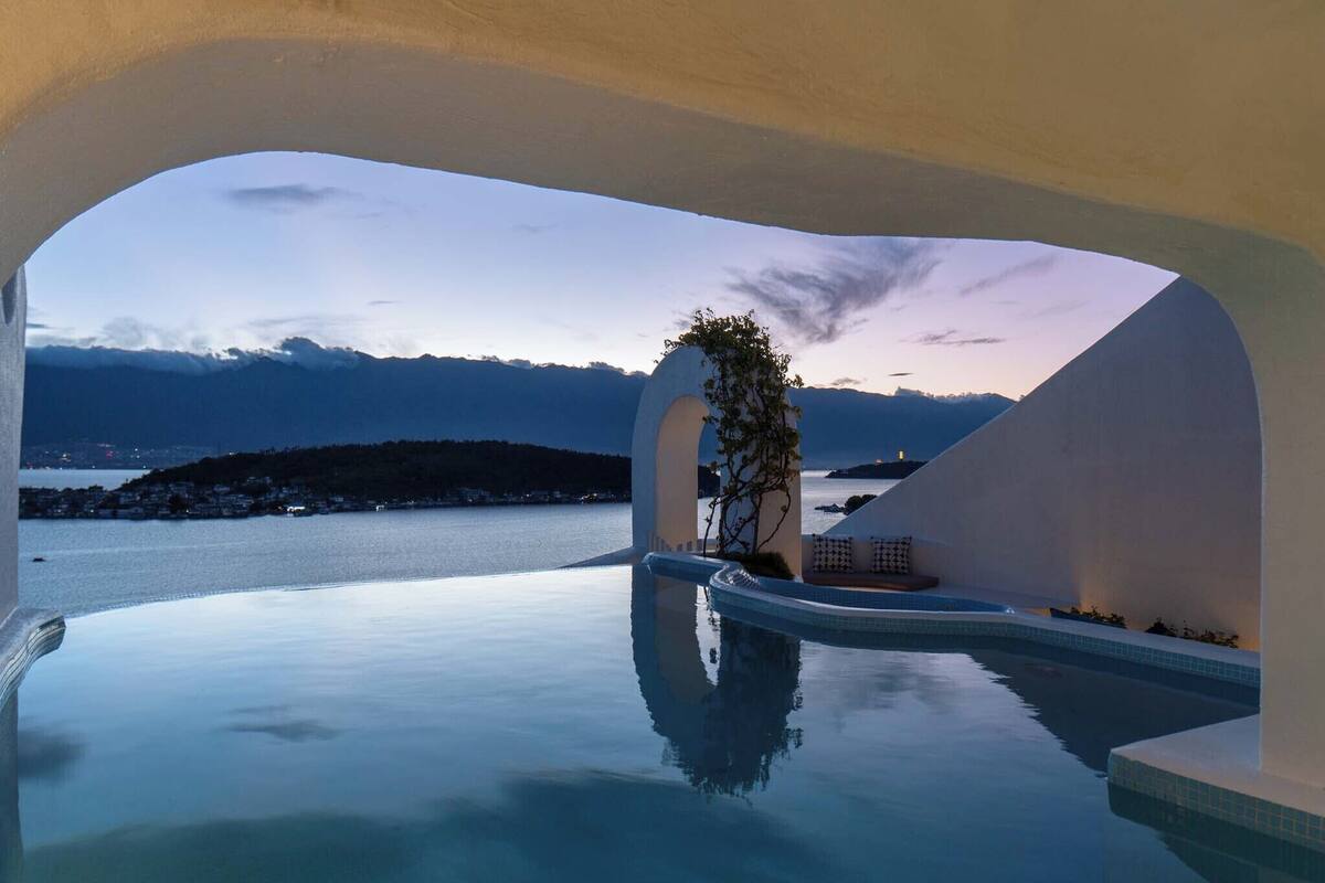 Une piscine à débordement offrant une vue dégagée sur la mer et les montagnes en arrière-plan.
