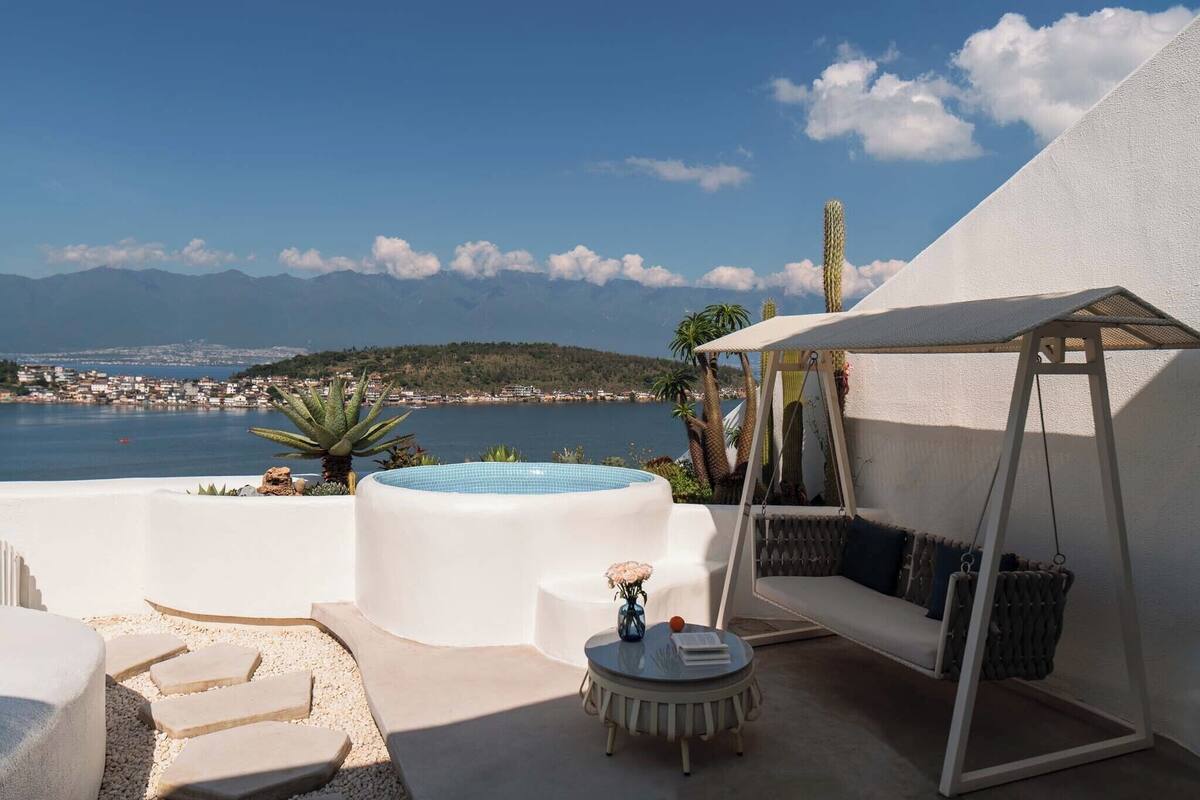 Une terrasse sur le toit avec un jacuzzi, un espace salon et une vue sur la mer et les montagnes.