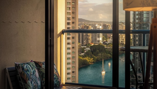 A high-rise building with a view of a river and boats, a balcony with a railing, and a window with a view of the cityscape. - Inviting Brisbane Family 2BR | CBD | Pool & Gym (Brisbane City)