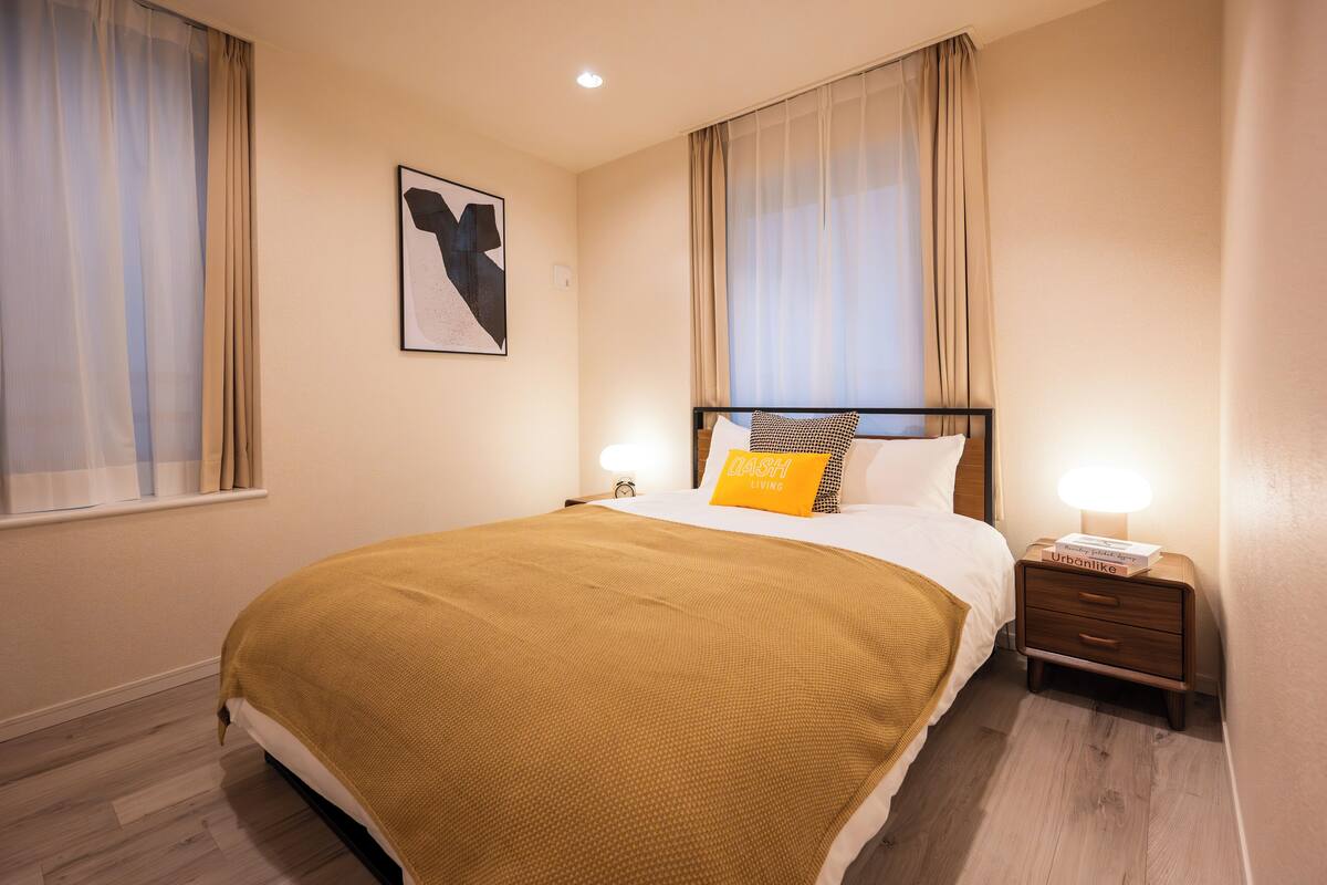 A hotel room with a bed, a nightstand, a lamp, and a framed picture on the wall.