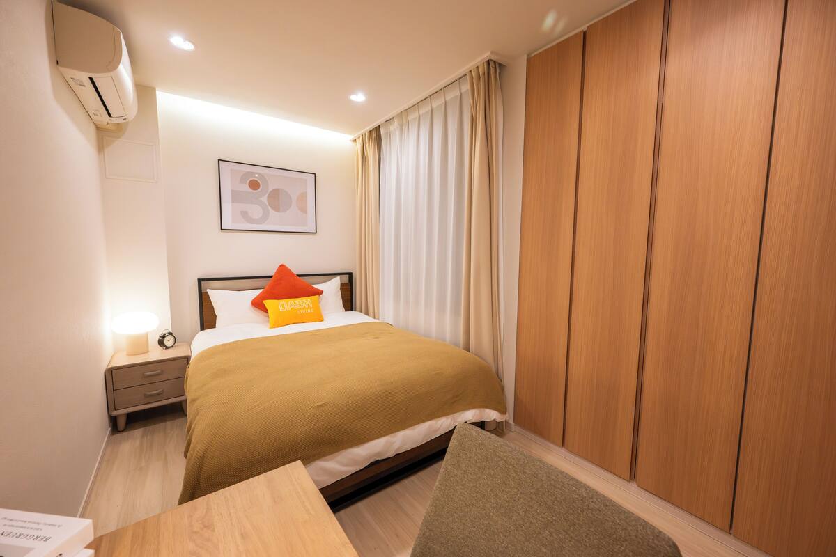 A hotel room with a bed, a nightstand, a desk, and a wardrobe.