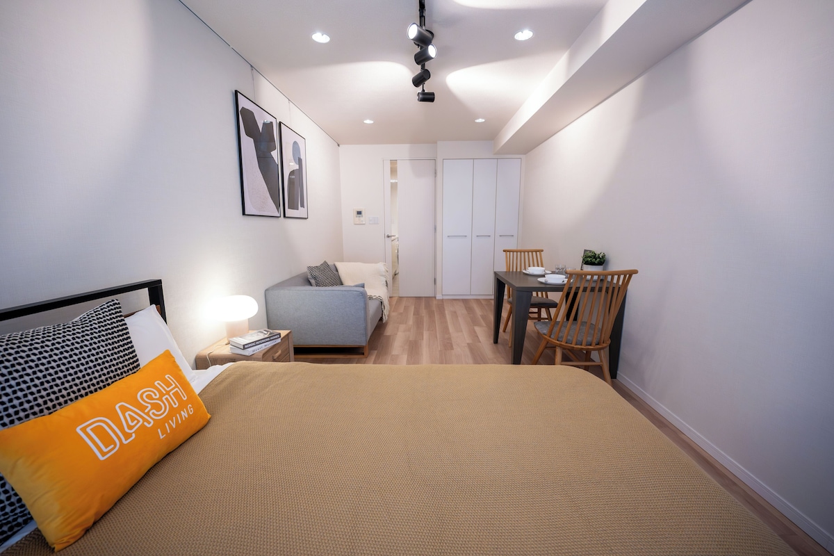 A modern bedroom with a bed, a desk, and a wardrobe.