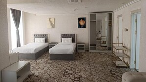 A hotel room with two beds, a wardrobe, a mirror, and a patterned floor. - The Tower Bukhara (Bukhara)