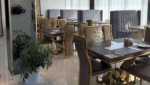 A dining area with tables and chairs, a potted plant, and a ceiling with a grid pattern. - The Tower Bukhara (Bukhara)