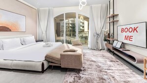 Een moderne hotelkamer met een groot bed, een bank, een televisie en een 'BOOK ME' bord.