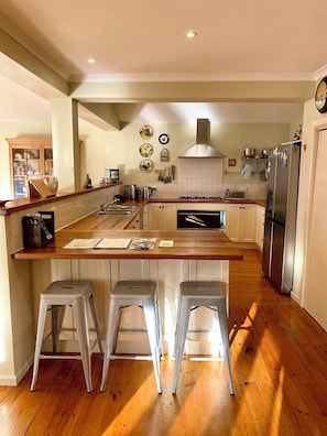 A kitchen with a central island, stainless steel appliances, and a wooden countertop.