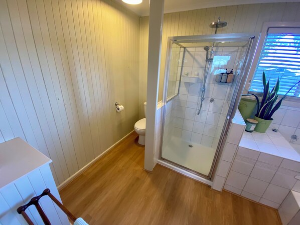 A bathroom with a glass-enclosed shower, a toilet, and a sink with a potted plant. - Absolute waterfront views, a cosy, country style retreat, set amongst the trees. (Newhaven)