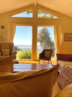 A room with a large window, a sofa, a chair, and a table.