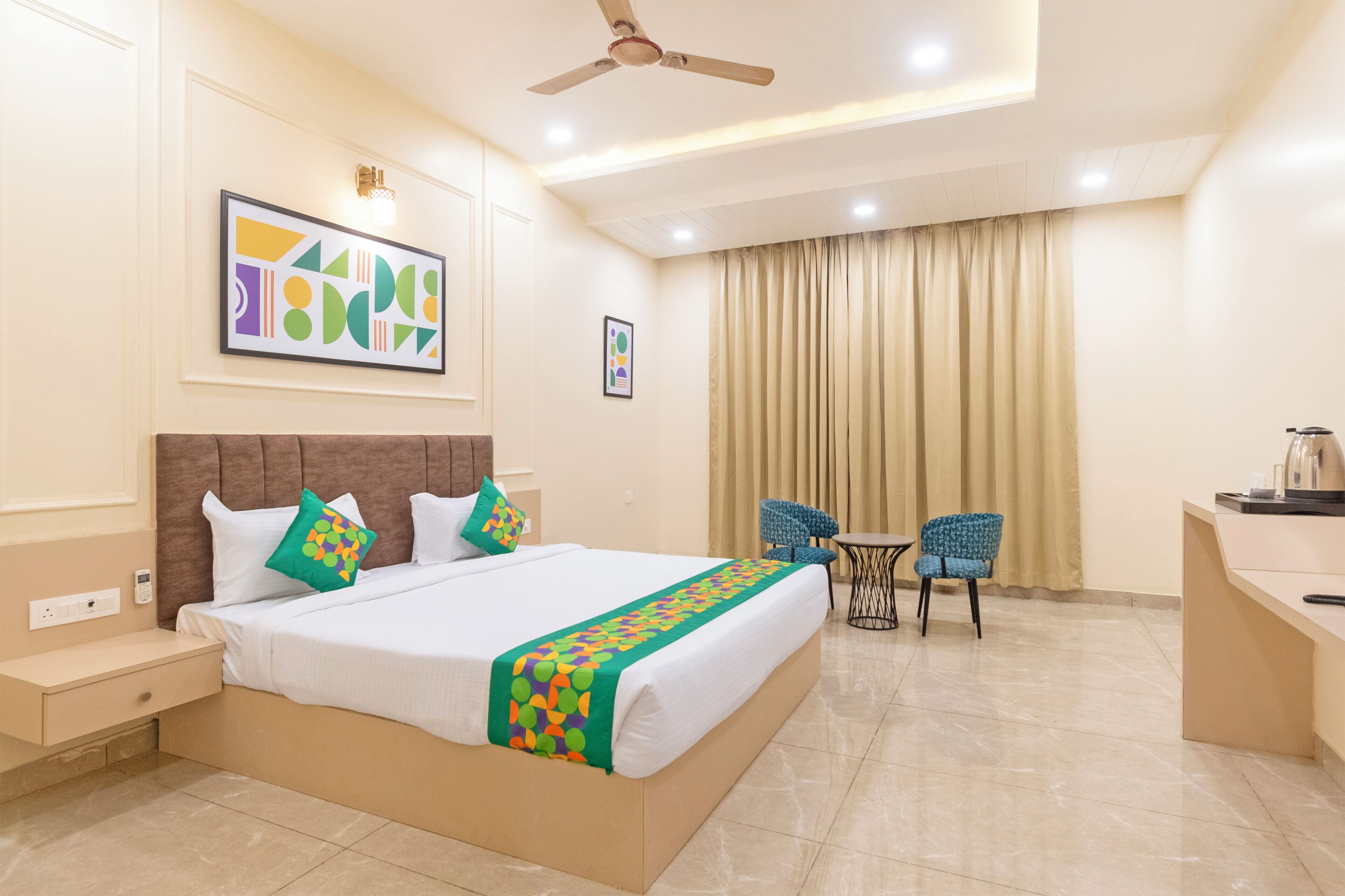 A hotel room with a bed, a desk, a chair, and a ceiling fan.