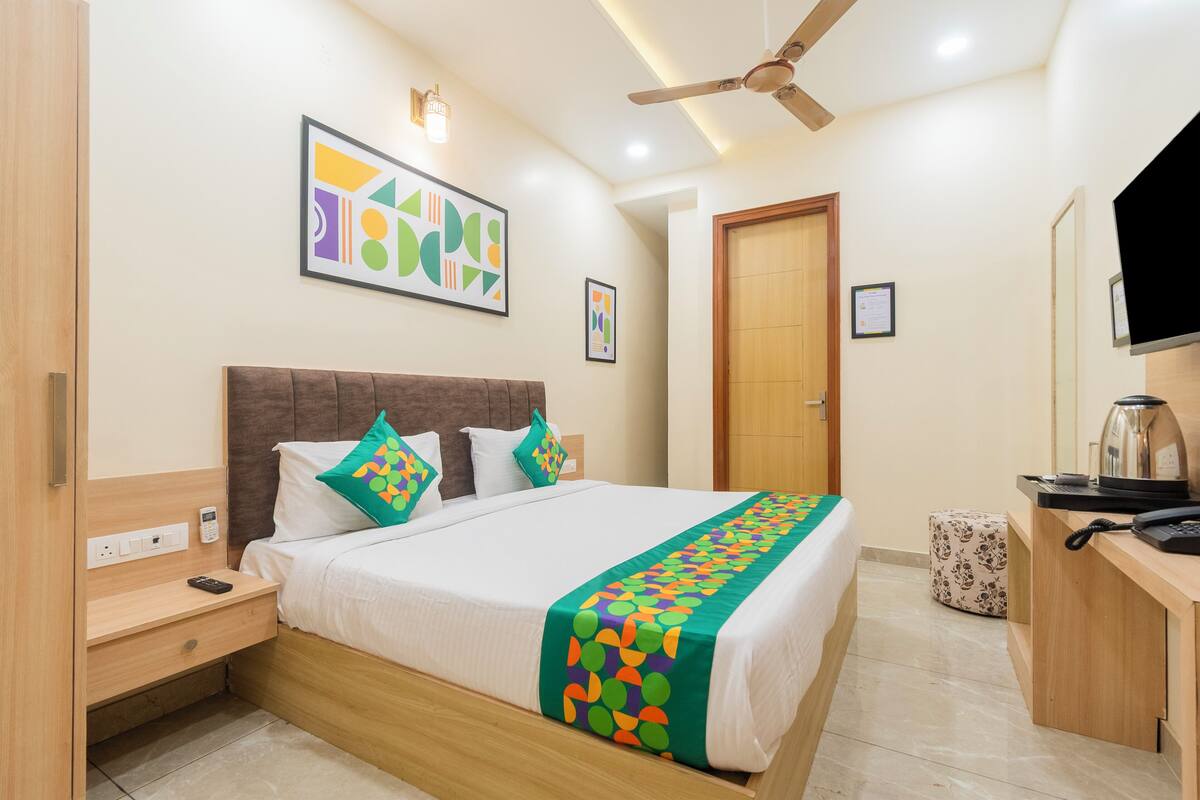 A hotel room with a bed, bedside table, nightstand, desk, and a ceiling fan.