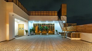 A spacious outdoor area with a patterned floor, a staircase, and a building entrance with large windows. - Treebo Indus (Jaipur)