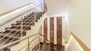 A modern staircase with a metal railing, a patterned wall, and a door with a geometric design. - Treebo Indus (Jaipur)