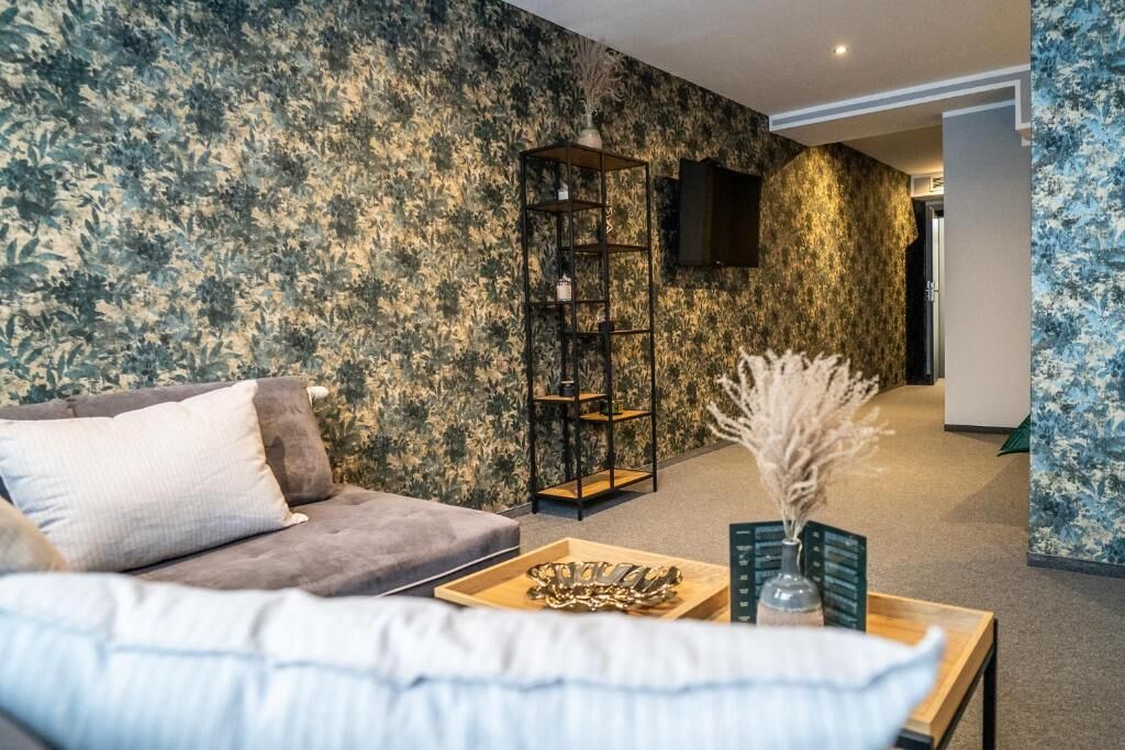 Ein Wohnzimmer mit einer Couch, einem Couchtisch mit Dekoration, einem Bücherregal und einem an der Wand befestigten Fernseher.