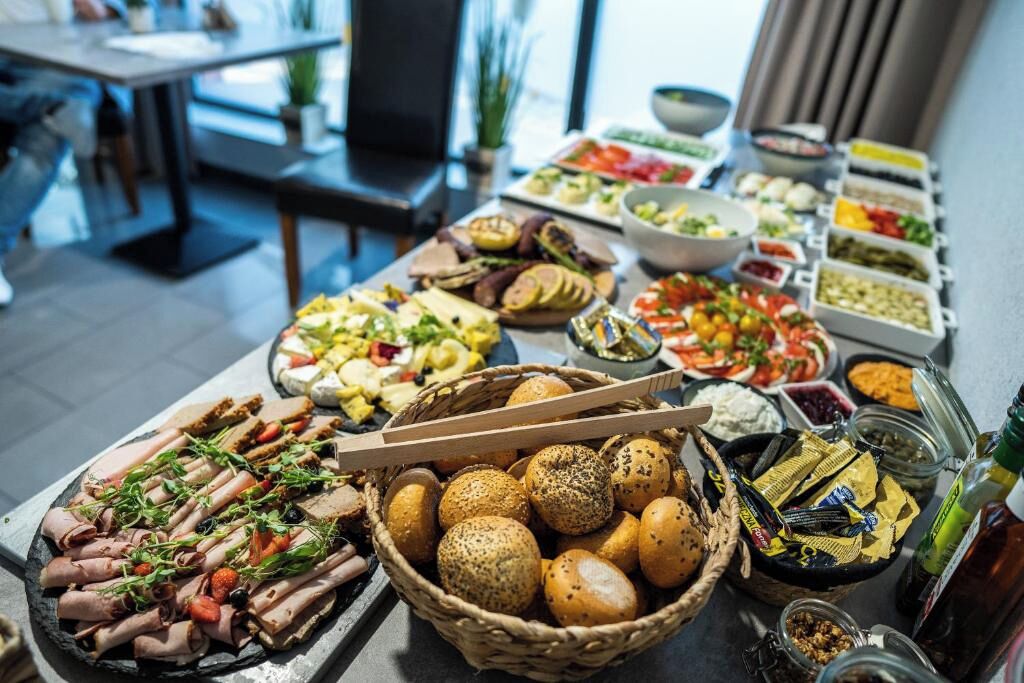A buffet table with various food items and a basket of bread.