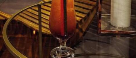 A glass table with a cocktail, a lemon slice, and a candle.