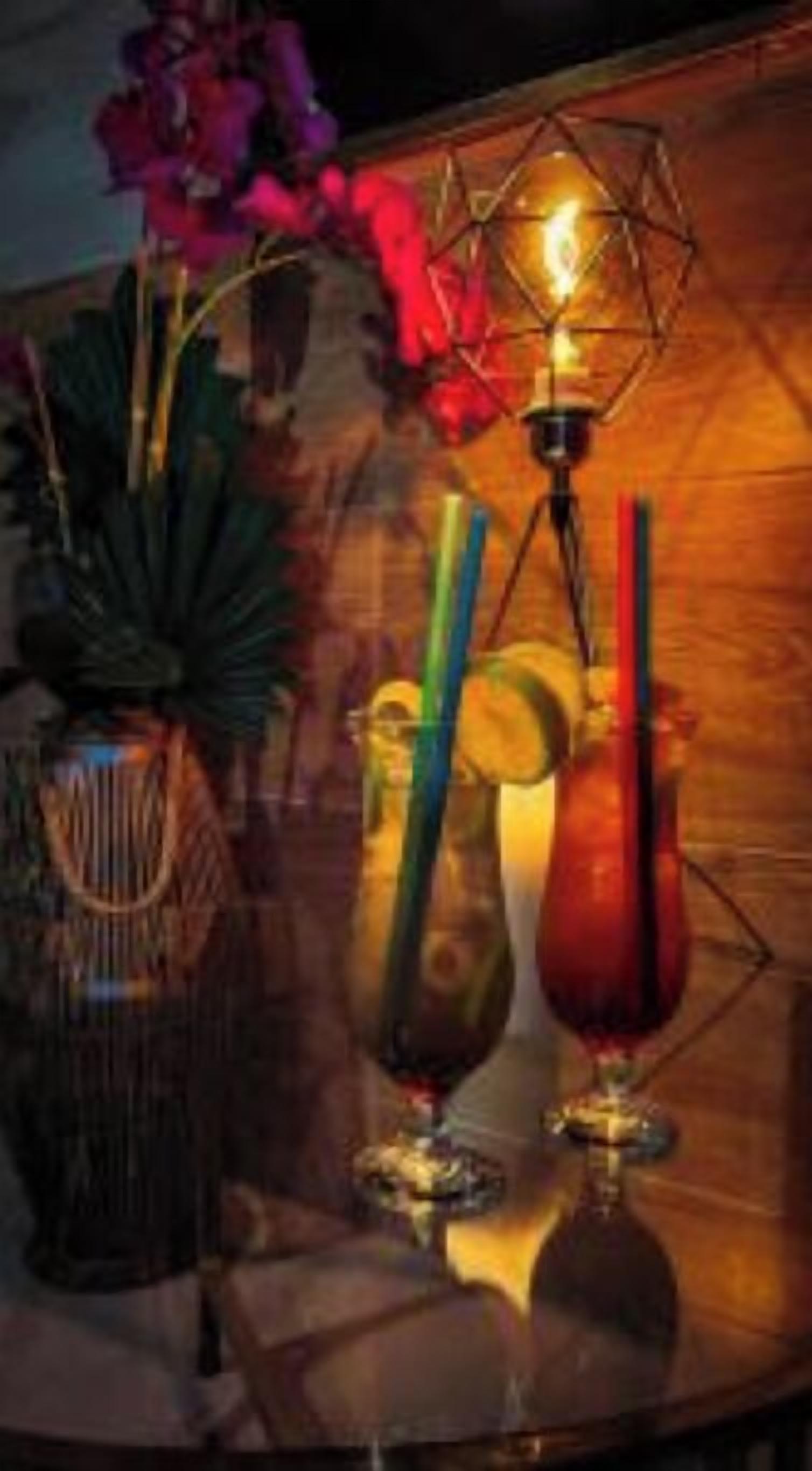 A bar area with a decorative lamp, a vase with flowers, and a glass with a straw.