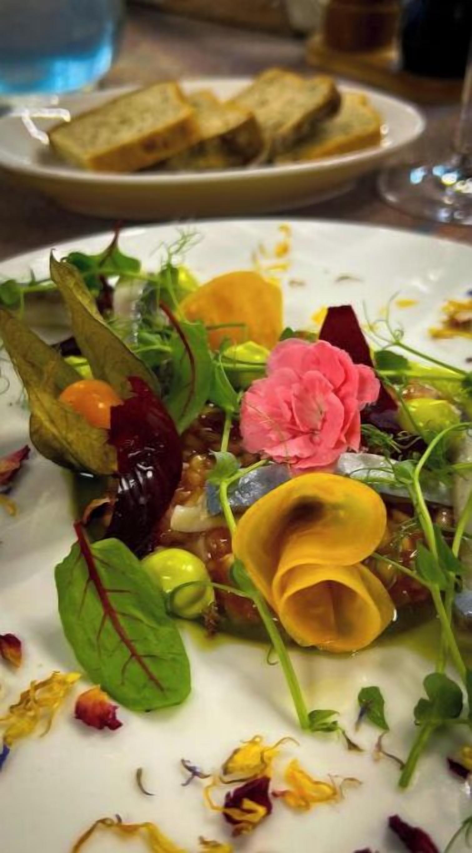 Un plato con ensalada, una flor y pan.