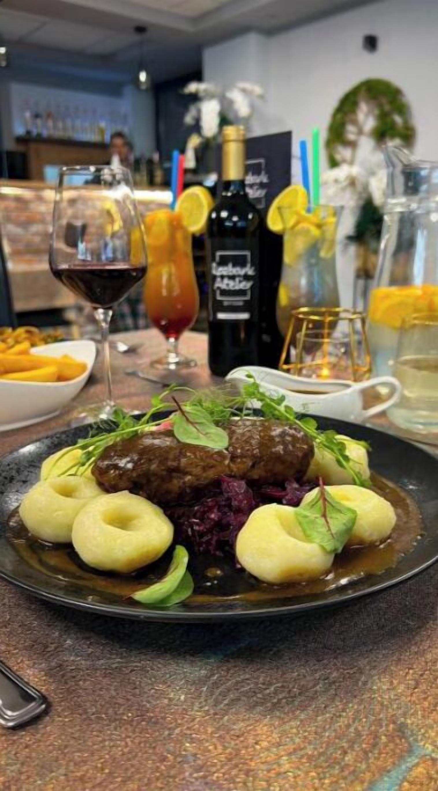 Un plato de comida con una botella de vino y una copa de vino tinto sobre una mesa.
