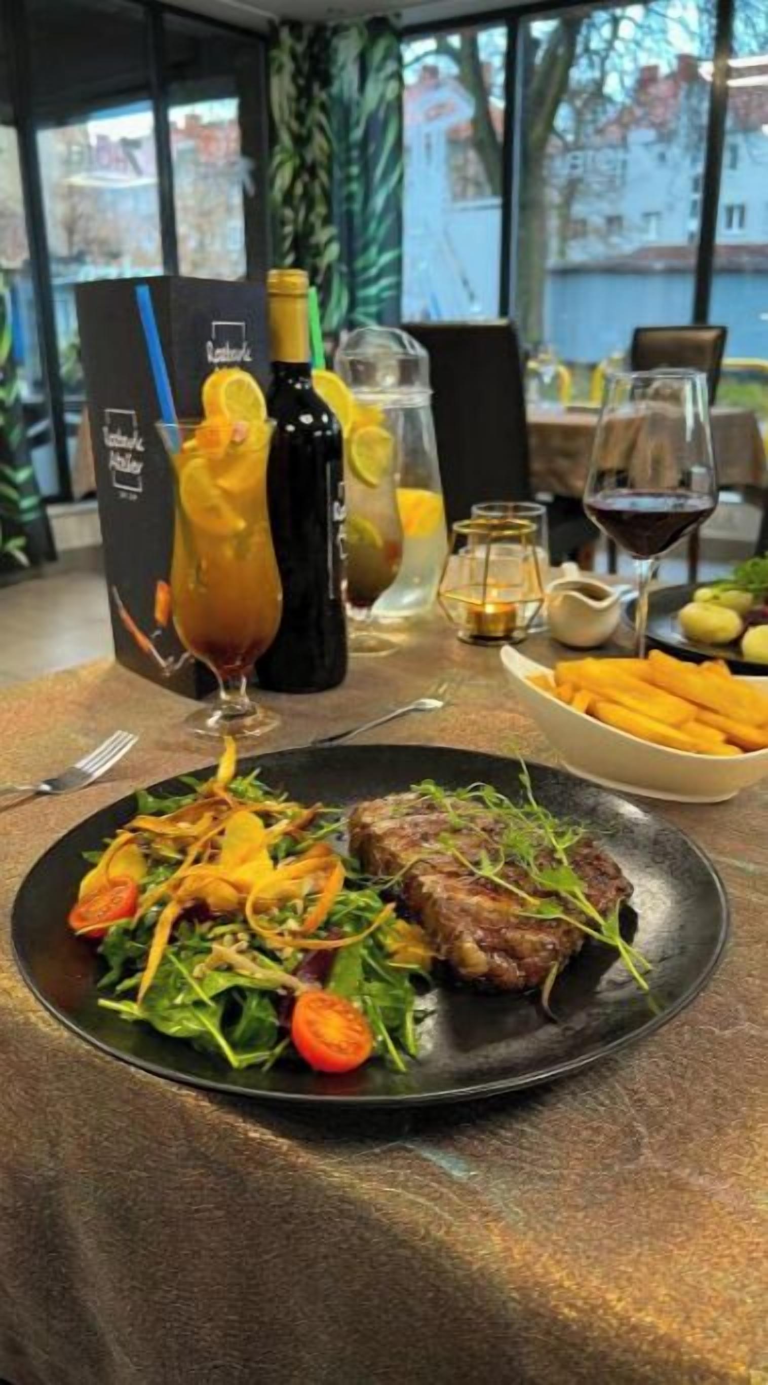 Ein Restaurantambiente mit einem Teller Essen, einer Weinflasche und einem Glas Saft auf dem Tisch.