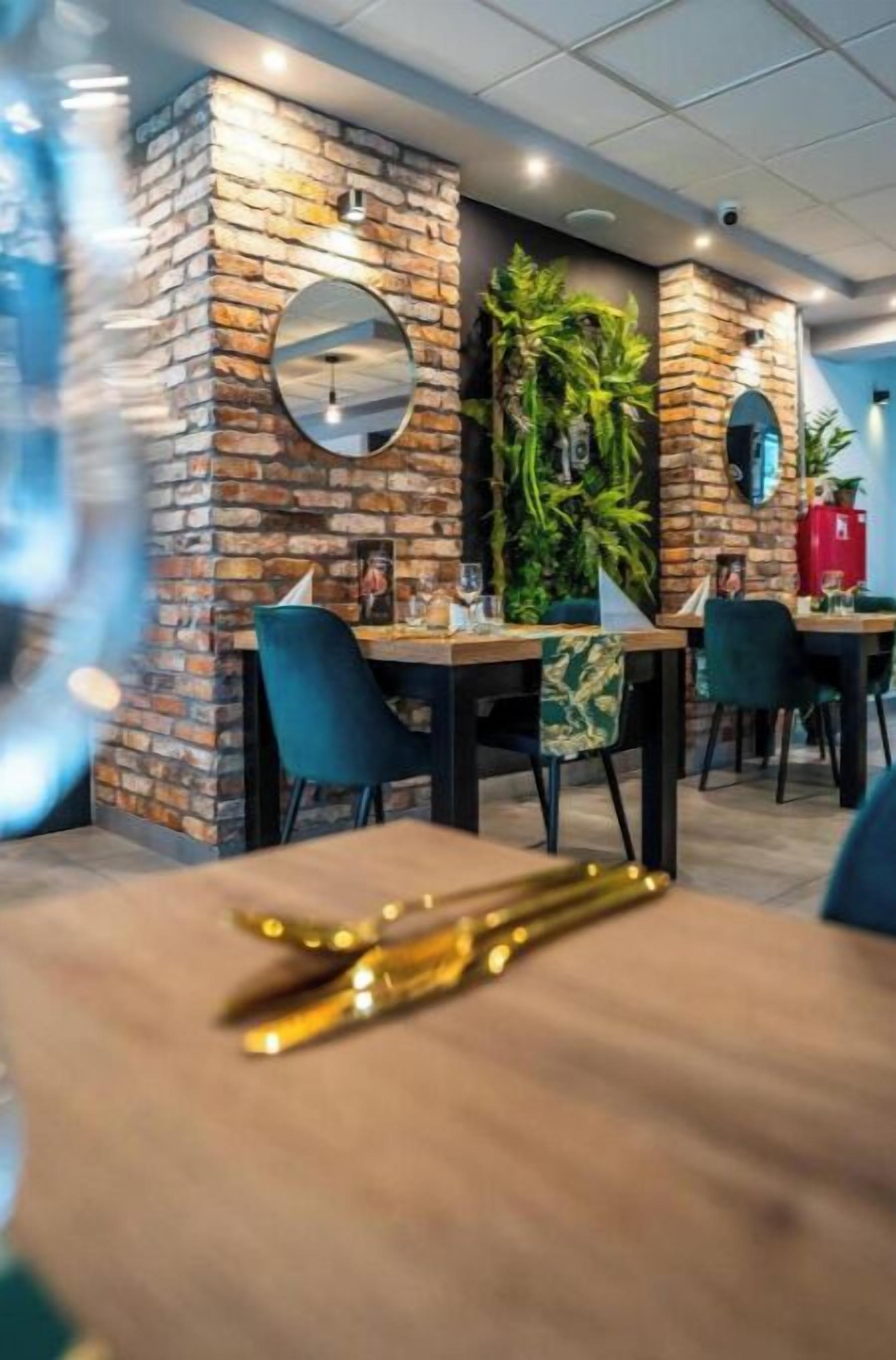 Un restaurante con paredes de ladrillo, espejos redondos y plantas verdes.