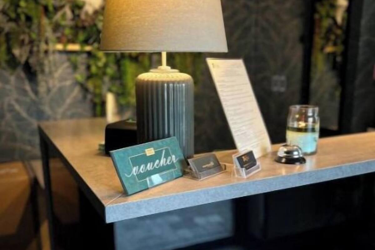 A reception desk with a lamp, a sign reading 'voucher,' a glass, and a small display case.