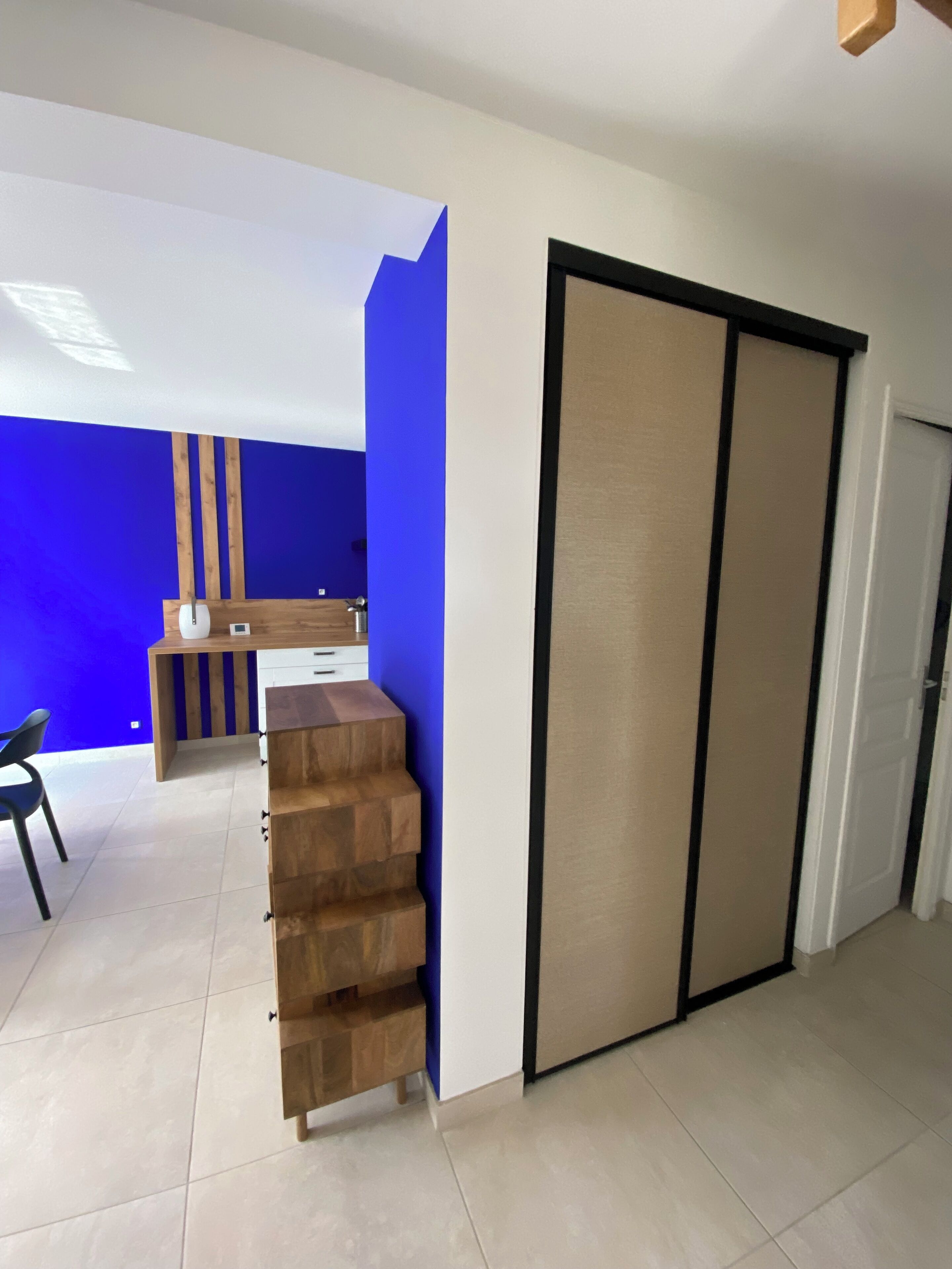 A modern interior with a blue accent wall, a wooden desk, and a sliding door.